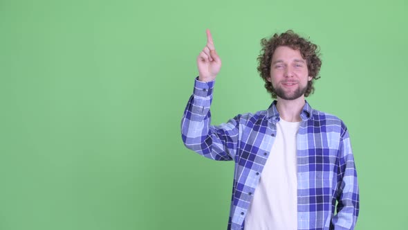 Happy Young Bearded Hipster Man Talking While Pointing Up alt