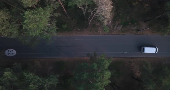 Flying, Tracking the Drone Behind a White Van, Along a Forest Road with a Bicycle Path with a Speed