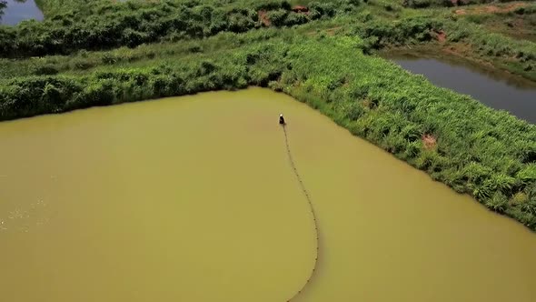 Drone view of fishermen in a fishing pond preparing a net to catch fish on a fish farm in rural Braz alt