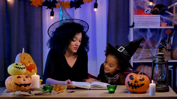 Little African American Girl in Festive Costume and Witch Hat Read Book alt