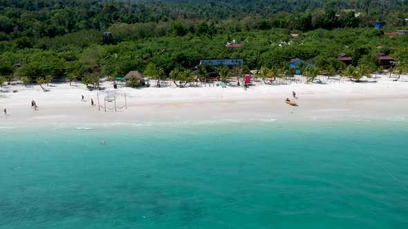 Aerial pan along white sand beach with turquoise blue sea in Koh Rong, Cambodia alt