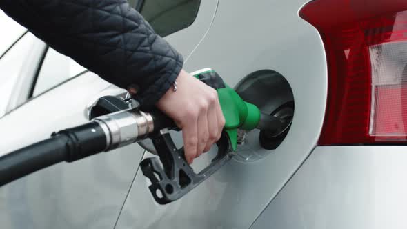Hand of a Gas Station Man is Putting Gasoline Into a Car alt