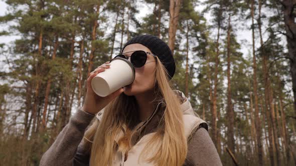 Steadycam Fly Around Shot. Woman Drink Coffee in the Pine Forest alt