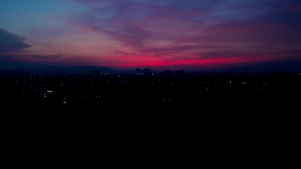 Drone moving towards a city after sunset dawn pink sky in India