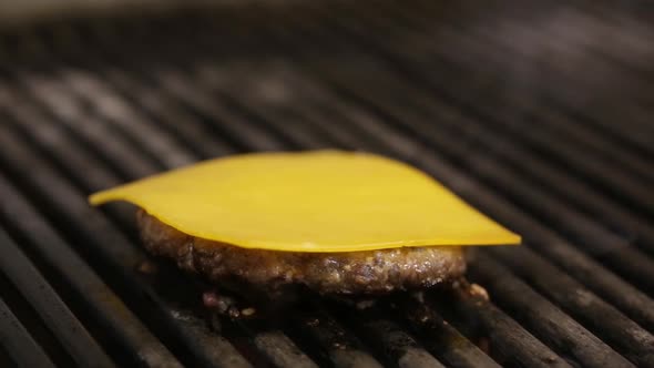 Close up Of  Cook Flipping Burger Meat on A Kitchen Grill and Adding Cheese