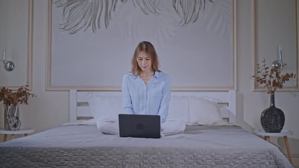 Blonde Female Wearing Pajamas Works in Bedroom