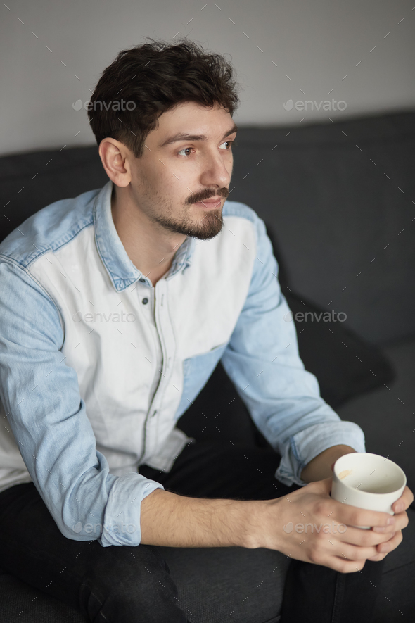 Freelancer resting with a cup of coffee on a couch while thinkin - Stock Photo - Images