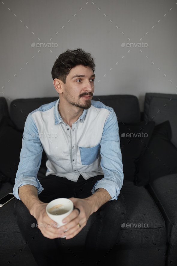 Freelancer resting with a cup of coffee on a couch while thinkin - Stock Photo - Images