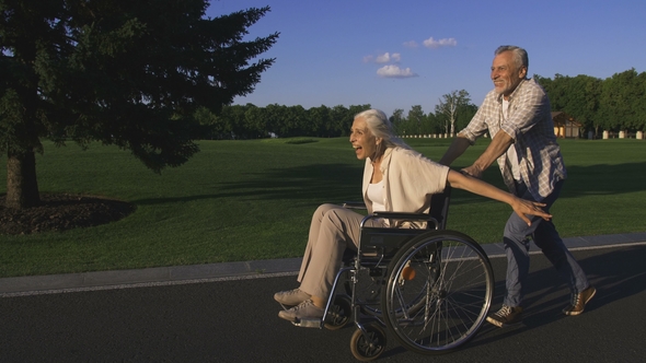 Aged Man Running While Pushing Wife in Wheelchair alt