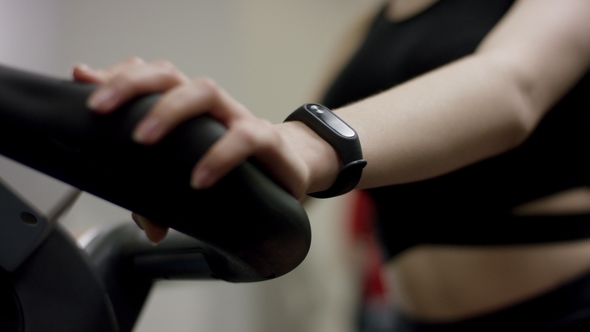 Cute Girl in Black Sport Wear Hardly Work on Exercise Bike with Focus on Hands in the New Gym