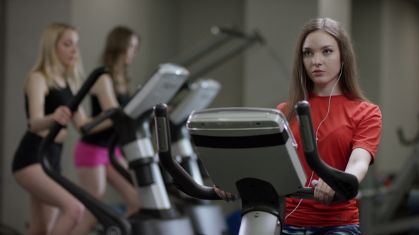 Nice Girl in Red Shirt Vigorously Works on Exercise Bike