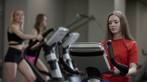 Girl in Red Shirt Vigorously Work on Exercise Bike and Take a Bottle of Water To Drink