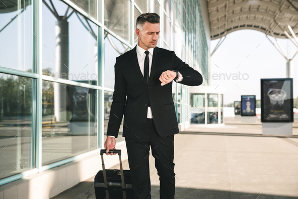 Serious businessman dressed in suit walking Stock Photo by vadymvdrobot