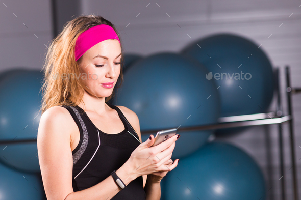 Sporty young woman with fitness tracker in gym Stock Photo by Satura_