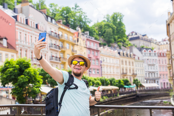 man taking selfie with mobile smart phone camera in european city Stock Photo by Satura_