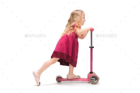 Smiling cute toddler girl three years riding a scooter over white background - Stock Photo - Images