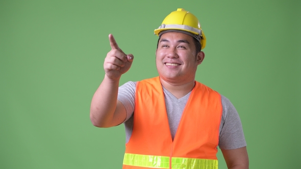 Young Handsome Overweight Asian Man Construction Worker Against Green ...