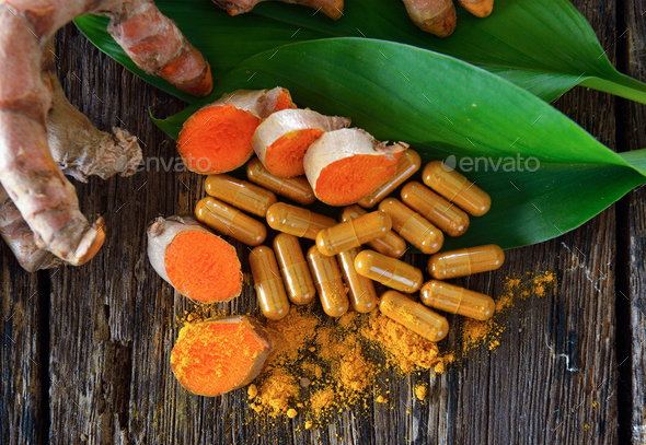 Turmeric powder and turmeric capsules on wooden background Stock Photo by sommai