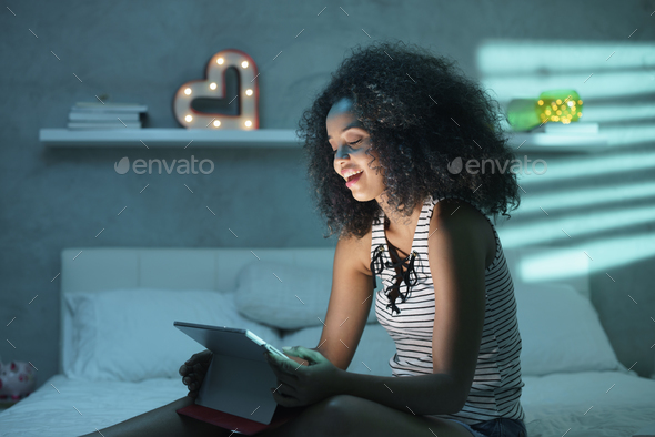 Young Black Woman Watching Movie With Laptop At Night Stock Photo by diego_cervo
