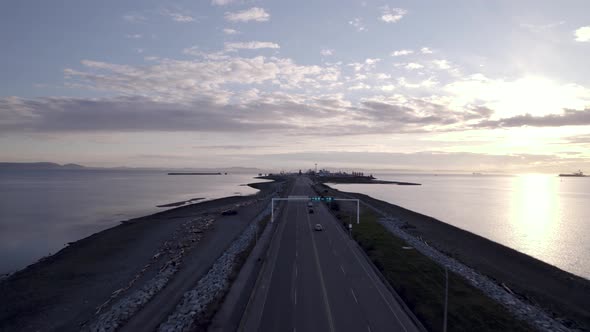 Aerial view of main highway with green traffic light, scenic road over the ocean with cars driving f alt