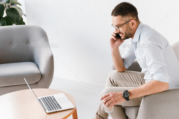 Photo of adult office man 30s in white shirt sitting in armchair Stock Photo by vadymvdrobot