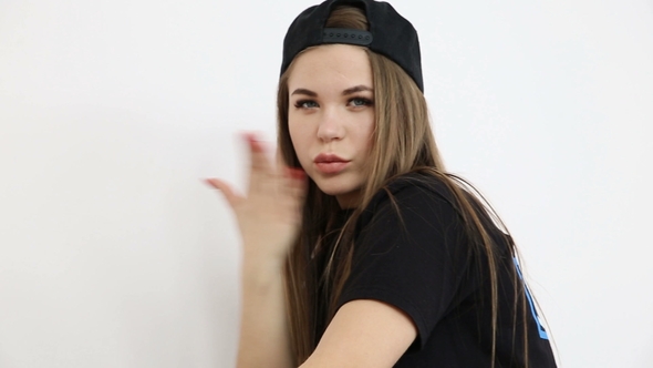 Teenage Girl in Trendy Hip Hop Clothes and Cap Posing Against White Wall