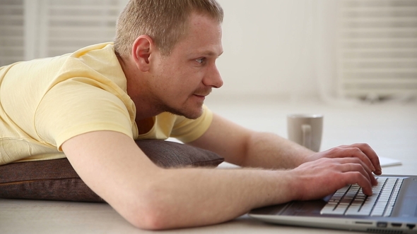 a Freelance Man Working at Home on the Floor Behind a Laptop