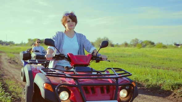 Adult Woman at the Wheel of an ATV in the Field the Camera Rotates Around Her alt