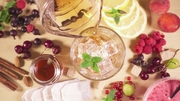 Cold Tea Pours Into a Glass with Ice