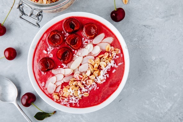 Cherry smoothie bowl with granola, almonds, coconut and fresh berries