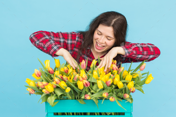 Charming female florist sorts out tulips in the box, selects them for the future flower arrangement Stock Photo by Satura_