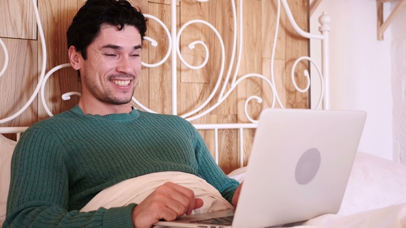 Online Video Chat on Laptop By Man Lying in Bed at Night alt