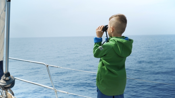Little Boy Stands on a Yacht and Looks in a Binocular alt