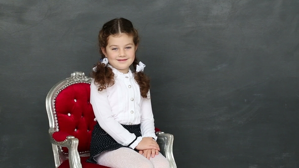 Little Girl Sitting in a Chair Near a School Board