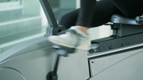 Asian Sport Women Riding a Stationary Bike in the Gym