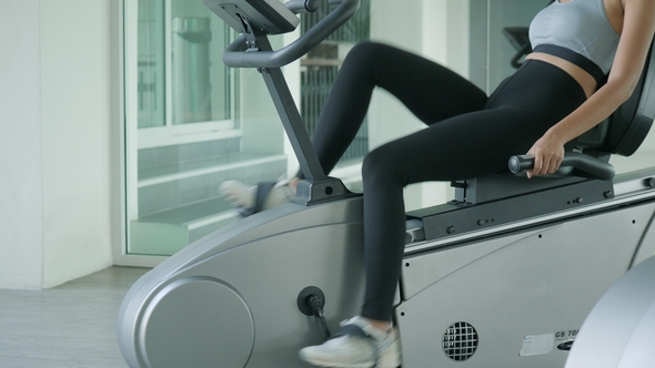 Asian Sport Women Riding a Stationary Bike in the Gym