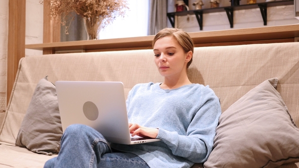 Woman Typing Email on Laptop, Sitting on Couch alt