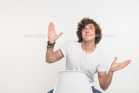 Handsome guy sitting on chair and dreaming with his hands up in white t-shirt with bracelet on hand. Stock Photo by Satura_