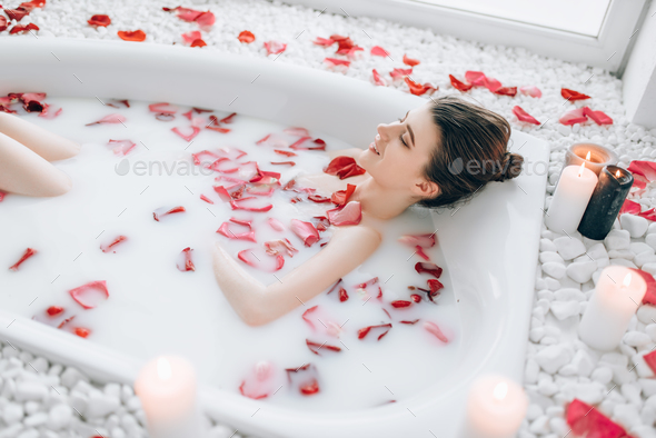Woman sleeps in the bath with foam, rose petals - Stock Photo - Images