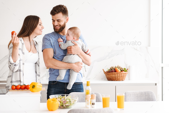 Amazing parents with their baby son cooking in kitchen. Stock Photo by vadymvdrobot