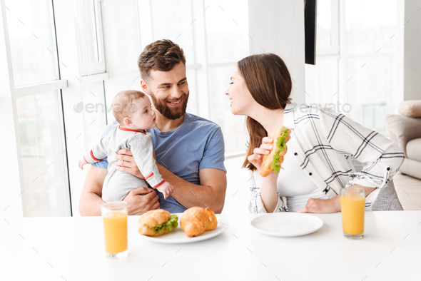 Funny young loving couple parents with their little baby son Stock Photo by vadymvdrobot