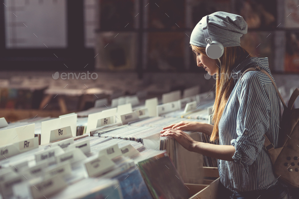 Young girl with headphones browsing records Stock Photo by AboutImages