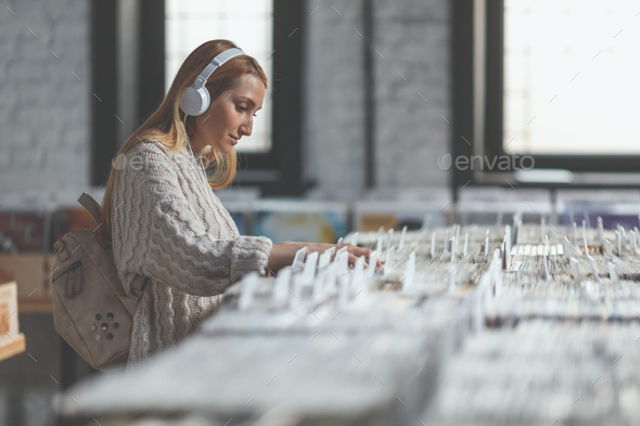 Attractive woman with headphones browsing records Stock Photo by AboutImages