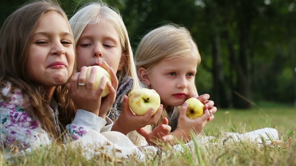 Values of Life - Childhood Friendship. Three Girls Eating Apples in the Park