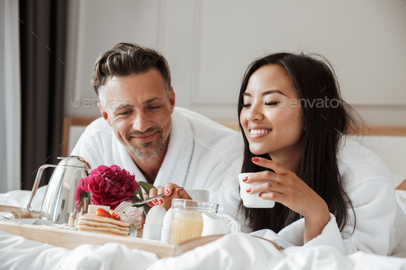 Photo of beautiful asian woman in white housecoat eating strawbe - Stock Photo - Images