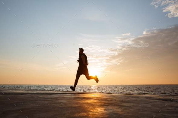 Image of muscular sporty man 30s in shorts and t-shirt running a Stock Photo by vadymvdrobot