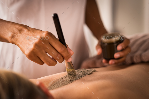 Beautician applying mud on body - Stock Photo - Images