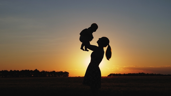 Silhouette of Mother with Child at Sunset alt
