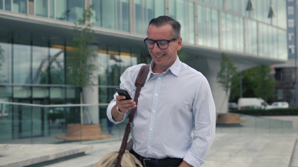 Man Walking and Using Smartphone