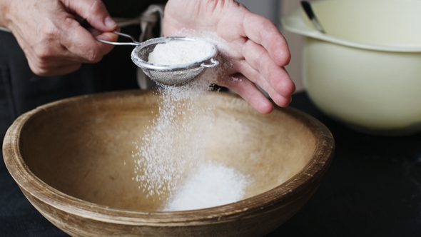 Female Hands Sifting Flour By Bowl alt